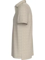 Chomba de corte regular color beige claro, con cuello tipo chomba, cartera de dos botones y logo de Tommy Hilfiger bordado en el pecho. Diseño de rayas en el interior del cuello.