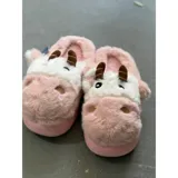 Pantuflas de peluche con diseño de vaca, confeccionadas en piel sintética suave. Cuentan con suela de goma antideslizante y diseño abierto en el talón.