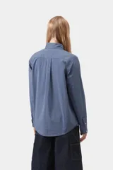 Camisa de manga larga Carhartt WIP modelo Groff, de corte regular y confeccionada en popelina de algodón ligera con estampado de cuadros. Cuenta con cierre frontal de botones, cuello con botones y un bolsillo aplicado en el pecho con etiqueta cuadrada tejida de la marca.