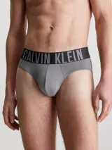 Pack de tres slips para hombre, confeccionados en microfibra de poliéster reciclado y elastano. El slip visible es de color gris liso con cinturilla elástica negra que lleva el logo de Calvin Klein en gris.