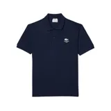 Remera polo Lacoste de manga corta en color azul marino, confeccionada en tejido de punto piqué. Presenta cuello clásico, cierre frontal de dos botones y el logo de la marca bordado en el pecho junto con la inscripción Lacoste Paris.