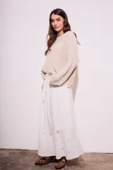 Falda larga blanca de viscosa y lino, con cintura elastizada y cordón ajustable. Presenta bordado calado con motivos florales en el ruedo.