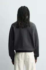 Sudadera de corte relajado con efecto lavado, confeccionada en algodón con interior de rizo. Presenta cuello redondo, manga larga raglán y acabados en rib.