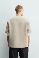 Sudadera de manga corta con corte relajado, confeccionada en tejido técnico compacto de algodón con elasticidad. Presenta cuello redondo y detalle de tacha metálica en la espalda.