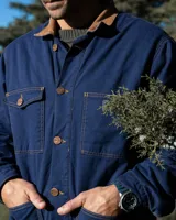 Campera estilo workwear de Denali, confeccionada en canvas resistente color azul royal. Cuenta con interior forrado en corderito sherpa, cuello de pana en color tostado, cierre frontal con botones metálicos color cobre y cuatro bolsillos frontales.
