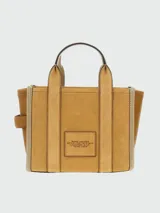Cartera tipo tote de Marc Jacobs, confeccionada en una combinación de gamuza y cuero texturizado en tonos tierra. Presenta el logo 'THE TOTE BAG' estampado en el frente, doble asa superior y correa ajustable extraíble.