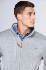 Campera deportiva de tejido tipo polar en color gris jaspeado, con cuello alto, cierre frontal completo, bolsillos laterales y bolsillo en el pecho con cierre. Presenta detalles en cuero sintético y logo bordado en el pecho.