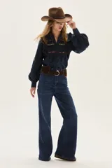 Blusa azul marino de algodón con volados en los hombros, mangas largas abullonadas y detalles de bordados florales y geométricos en el pecho y las mangas.