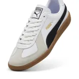 Championes Puma modelo Army Trainer, color blanco con detalles en negro y superposiciones de gamuza gris claro en la puntera. Cuenta con suela de goma tipo 'gum' y la inscripción de la marca en dorado en el lateral.