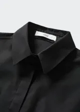 Camisa básica de algodón color negro, con cuello camisero, manga larga con puños abotonados y cierre frontal de botones.