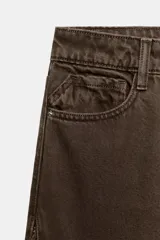 Jeans de tiro medio y corte recto, color marrón chocolate. Presenta un diseño de cinco bolsillos y detalles laterales con tejido de crochet a tono a lo largo de las piernas.