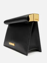 Bolso de cuero color negro modelo La Petite Pochette Rond C de Jacquemus, con silueta de sobre, solapa superior enrollada con broche magnético, extremos metálicos en plata y oro, y logo grabado en letras doradas en el frente.