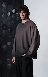 Buzo de cuello redondo con efecto de lavado maltinto o nevado. Presenta un corte oversize con hombros caídos, costuras expuestas a contratono y detalles de roturas desgastadas en el cuello, puños y ruedo.