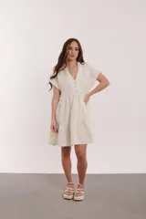 Vestido corto azul con cuello camisero, escote en V, mangas cortas y falda escalonada con volantes.