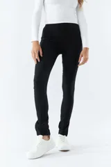 Pantalón negro de tiro alto, corte ajustado y aberturas en los tobillos.