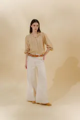 Pantalón de jean gris oscuro, estilo sastrero de tiro medio bajo y corte ancho (wide leg). Presenta costuras marcadas en el frente y un cinturón trenzado marrón con hebilla metálica.