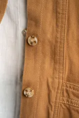 Sobrecamisa de algodón en color camel, con cuello camisero en contraste de tono oscuro, cierre frontal de botones y bolsillos laterales aplicados.