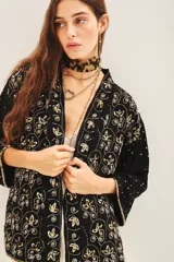 Kimono de corte holgado en color negro, con mangas tres cuartos y diseño bordado con motivos florales y detalles en hilo dorado. Presenta un cierre frontal anudado y forro interior.