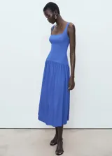 Vestido midi de color azul, sin mangas, con tirantes anchos y cuello escotado cuadrado. Presenta un diseño ajustado en el torso con corte evase y falda de corte midi con vuelo.