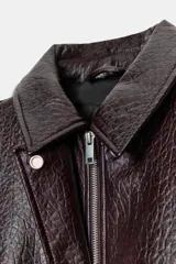 Chaqueta bomber de efecto piel en color marrón oscuro, con cuello solapa, cierre frontal con cremallera y botones, bolsillos delanteros, trabillas en los hombros y puños y bajo elásticos.