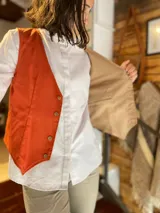 Chaleco reversible de lino, color naranja en el exterior y rayas finas en el interior, con cuello en V y cierre frontal de botones.