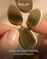 Caravanas colgantes de acero con baño de oro, compuestas por múltiples piezas circulares y ovaladas de distintos tamaños dispuestas en cascada.