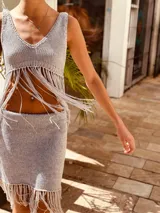Top tejido en lurex color gris, con escote en V y flecos en el ruedo.
