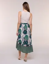 Vestido midi combinado de corte fluido. Presenta un torso ajustado acanalado sin mangas, con cuello redondo y sisas clásicas. Cuenta con cintura elastizada con lazo para anudar y falda evasé con estampado floral y geométrico, finalizando con un volante en el ruedo.