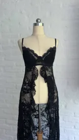 Top de encaje negro con diseño de corpiño tipo bralette y falda larga abierta al frente, con terminaciones de puntilla.