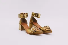 Zapato de cuero color dorado con punta fina, taco cuadrado y pulsera con hebilla y ojales.