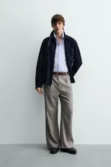 Pantalón relaxed fit color marrón con patrón de espiga, confeccionado en tejido con viscosa. Presenta pliegues frontales, bolsillos laterales y bolsillos traseros de vivo. Cierre frontal con cremallera y botón.