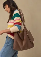 Cartera tipo shopper de símil gamuza marrón, con correa de hombro ajustable y un neceser externo con cierre.