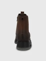 Bota tipo Chelsea de cuero marrón con paneles laterales elásticos en color negro. Presenta costuras reforzadas en el contorno y una suela robusta de poliuretano con base dentada en tono gris translúcido.