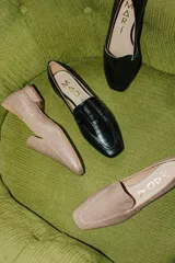 Mocasines bajos de cuero negro con textura croco y suela plana.