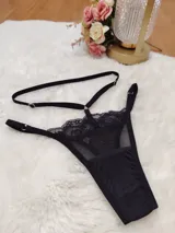 Tanga de tiro alto confeccionada en microtul y encaje negro, con diseño de tiras regulables en la cintura y forro de algodón.