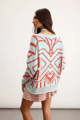 Buzo oversize de punto color marfil con diseño geométrico jacquard en tonos rosado, amarillo, celeste y marrón. Cuenta con cuello redondo y mangas largas.
