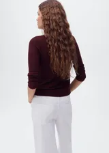 Jersey de punto fino con acabado brillante de lúrex, cuello en pico y manga larga. Presenta un diseño recto y entallado.