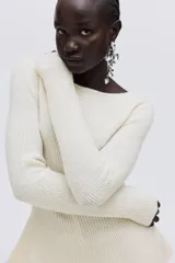 Buzo de punto acanalado color crema, con ajuste entallado, escote bote, mangas largas y detalle de peplum en la cintura.