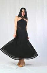 Vestido largo negro con escote halter y textura calada. Presenta un corte en la cintura con transparencia y un ruedo con detalle calado que deja ver la pierna.