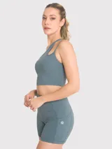 Top deportivo asimétrico de un hombro color verde azulado, con abertura y tirante fino en el hombro. Incluye sujetador interno con almohadillas removibles y soporte medio.