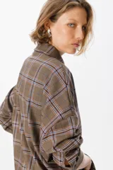 Camisa de corte oversize con estampado de cuadros, cuello clásico, cierre frontal con botones y bolsillo en el pecho.