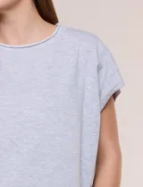 Remera de silueta amplia y relajada de color gris melange, confeccionada en algodón con poliéster. Presenta escote a la base con terminación rústica de borde enrollado, mangas cortas de hombro caído sin dobladillo y ruedo curvo con la parte posterior más larga.