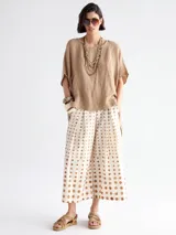 Pantalón palazzo color crudo con estampado de lunares marrones.
