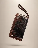 Billetera rectangular de cuero marrón con cierre perimetral y correa de muñeca. Presenta un diseño decorativo con costuras en forma de X en la parte frontal.