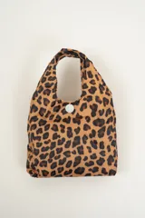 Bolso tipo tote bag con estampado animal print de cebra en blanco y negro, con cierre de botón a presión en la parte superior.