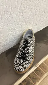 Championes de cuero con estampado animal print en blanco y negro, cordones negros y suela de goma color caramelo.