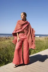 Ruana de edición limitada, tejida artesanalmente en lana merino color terracota, con detalles de lino teñido artesanalmente en los bordes y flecos.