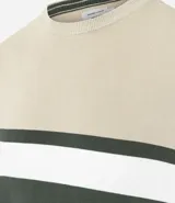 Suéter de punto con cuello redondo y manga larga, diseñado con un patrón de bloques de color en tonos beige, blanco y gris. Presenta un corte regular que se ajusta de forma anatómica al cuerpo.