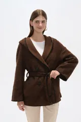 Chaqueta blanca de corte holgado con capucha, cierre frontal cruzado con botones y cinturón de tela ajustable. Presenta detalles de costuras decorativas en color negro en los bordes, solapas, bolsillos y cinturón.