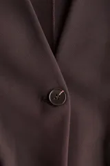 Blazer de punto marrón oscuro, de corte entallado con hombreras, escote en V sin cuello, cierre de un solo botón y bolsillos frontales con solapa.
